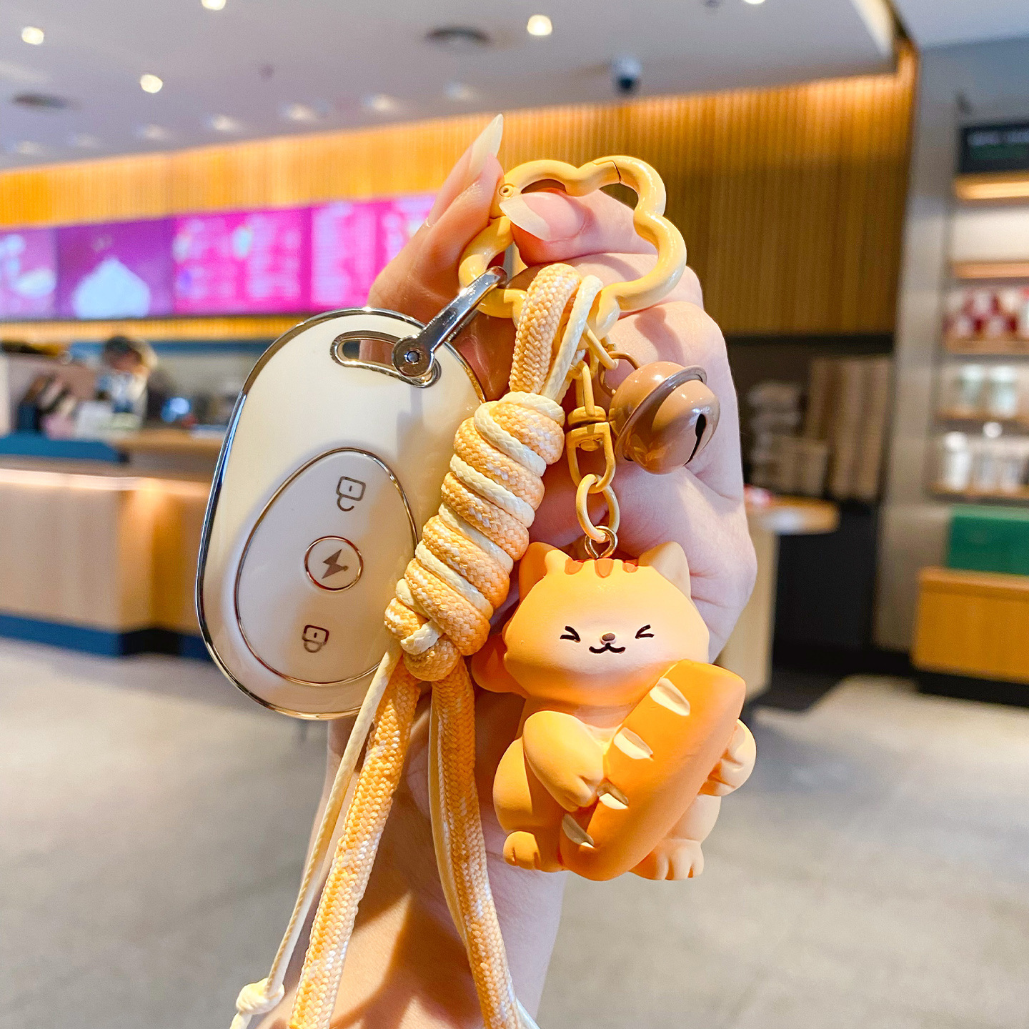 Cute bread cat keychain charm attached to a car key fob