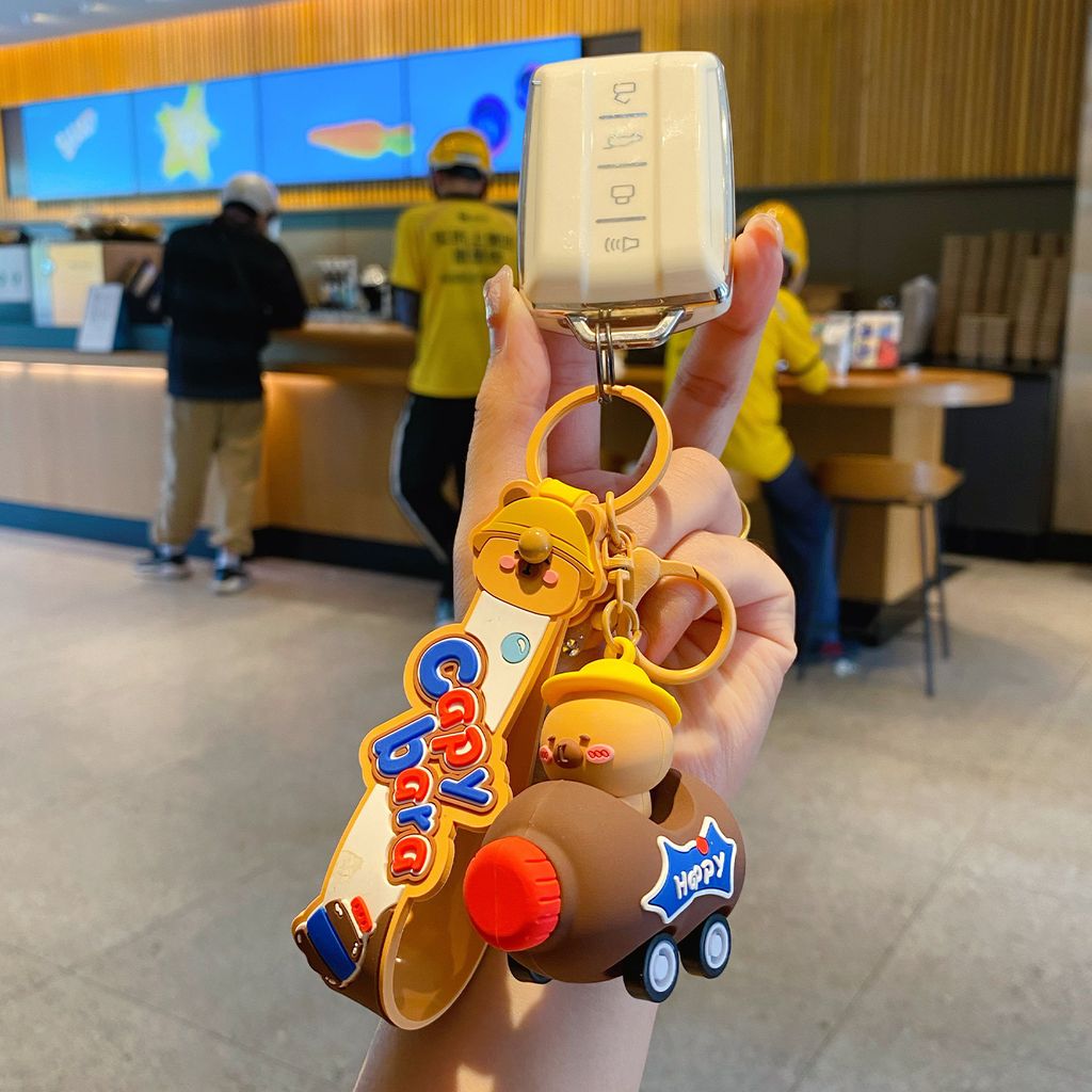 Cute capybara in a brown cola bottle car keychain charm attached to a car key fob