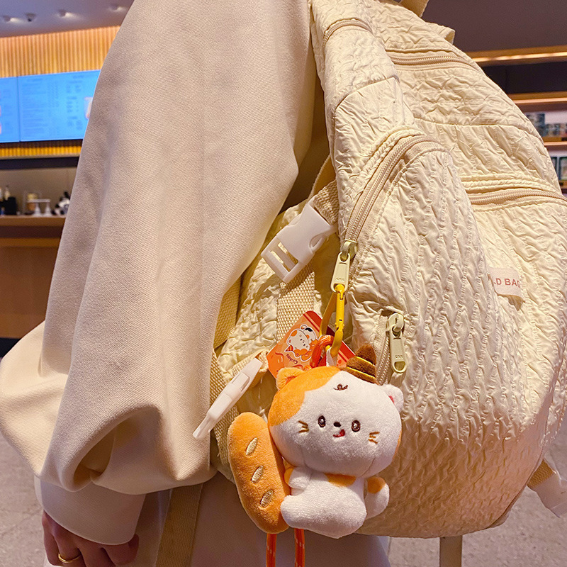 Baguette cat plush keychain charm hanging on a bag