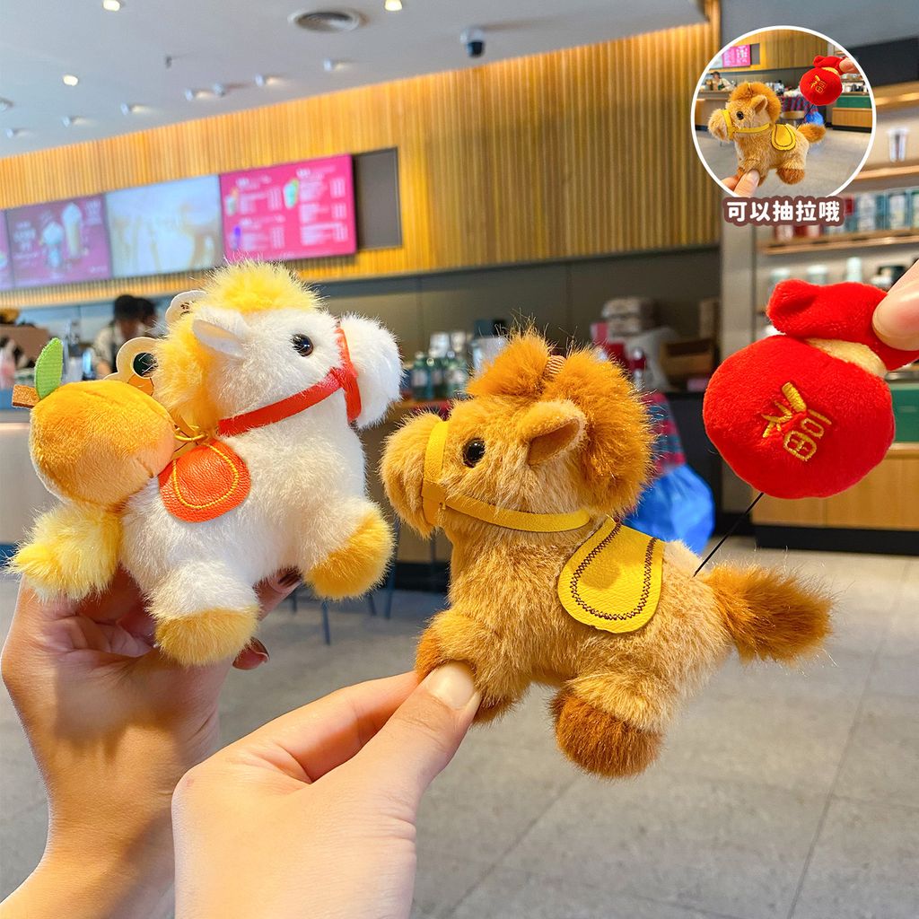 Hand pulling the extendable charm on the fortune horse plush keychain beside the good luck horse design