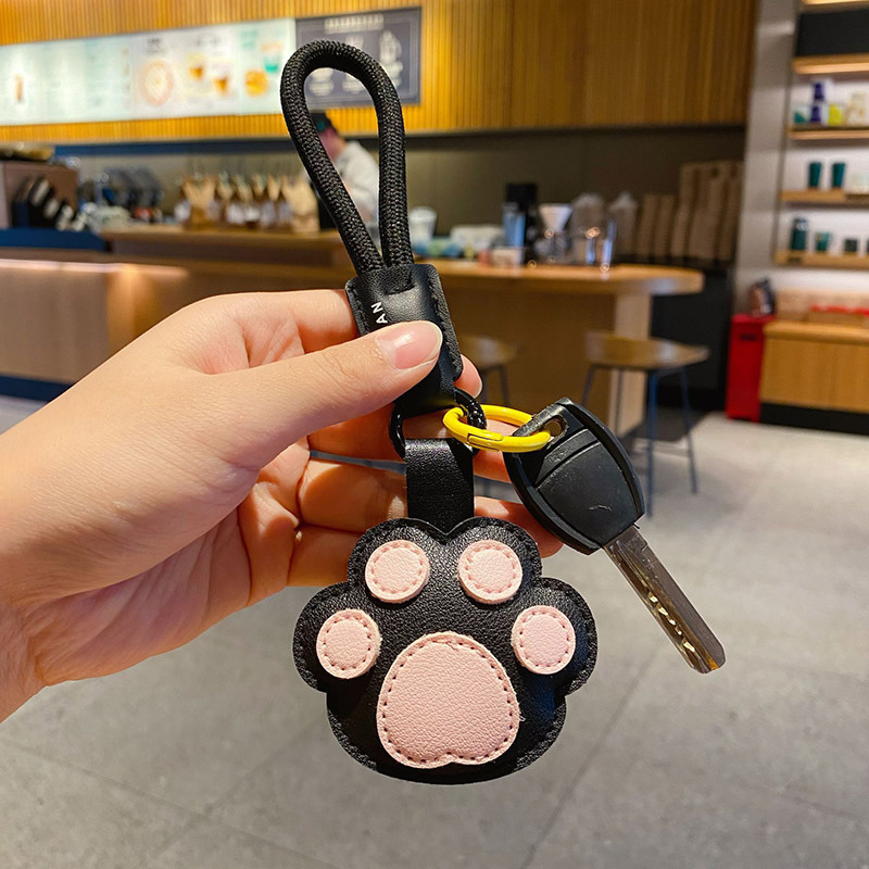 Cute paw leather keychain charm attached to a car key