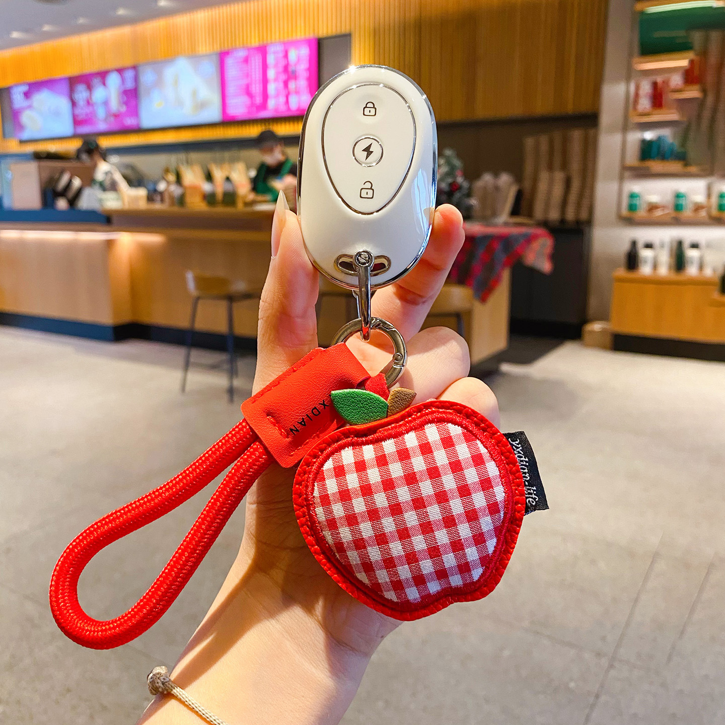Apple gingham leather keychain charm attached to a car key fob