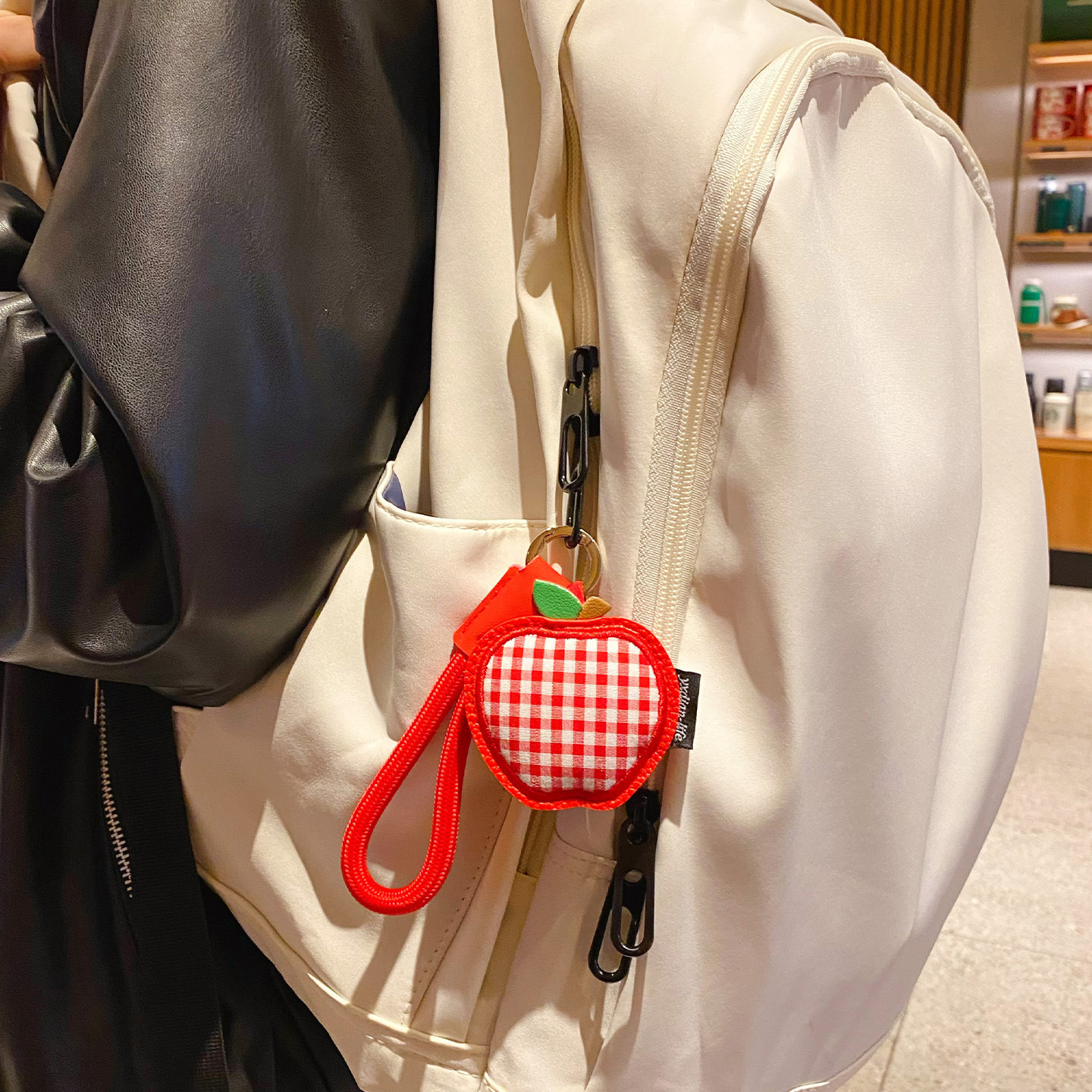 Apple gingham leather keychain charm hanging on a bag