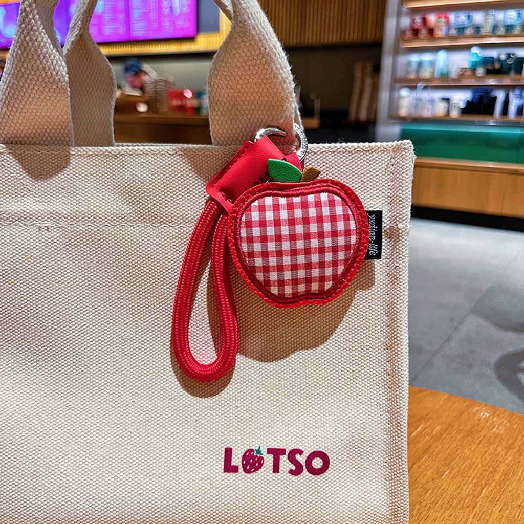 Apple gingham leather keychain charm hanging on a bag
