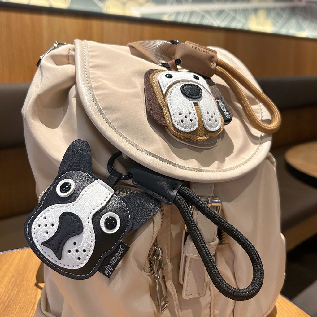 Beagle and Bulldog leather dog keychain charms hanging on a bag