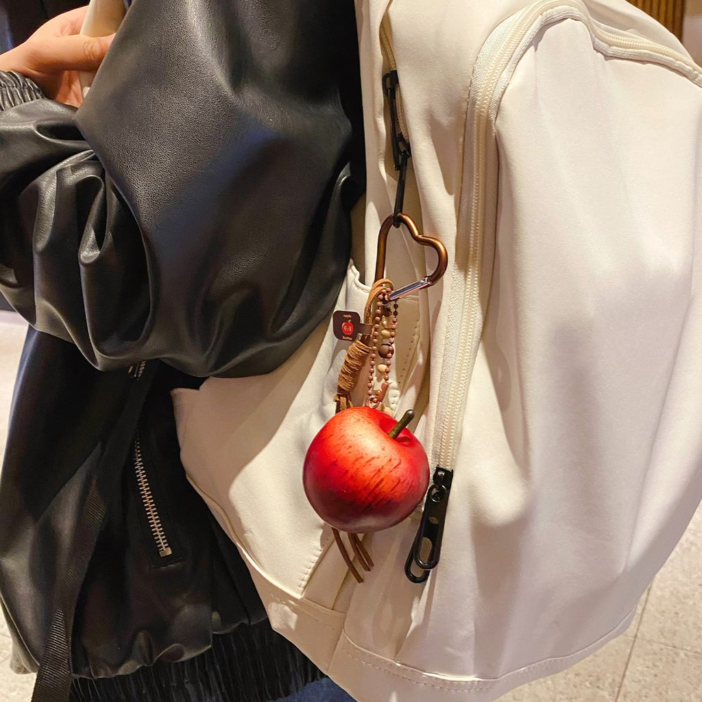 Lucky apple keychain charm hanging on a bag with a red apple design