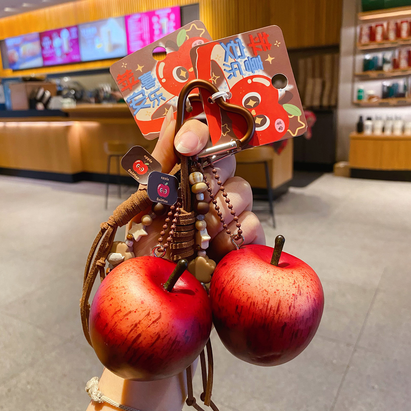 Two lucky apple keychain charms held in hand