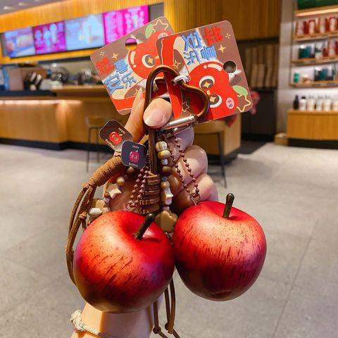 Two lucky apple keychain charms held in hand