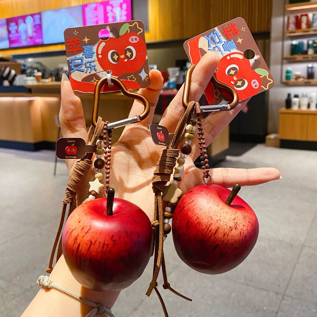 Two lucky apple keychain charms held in hand