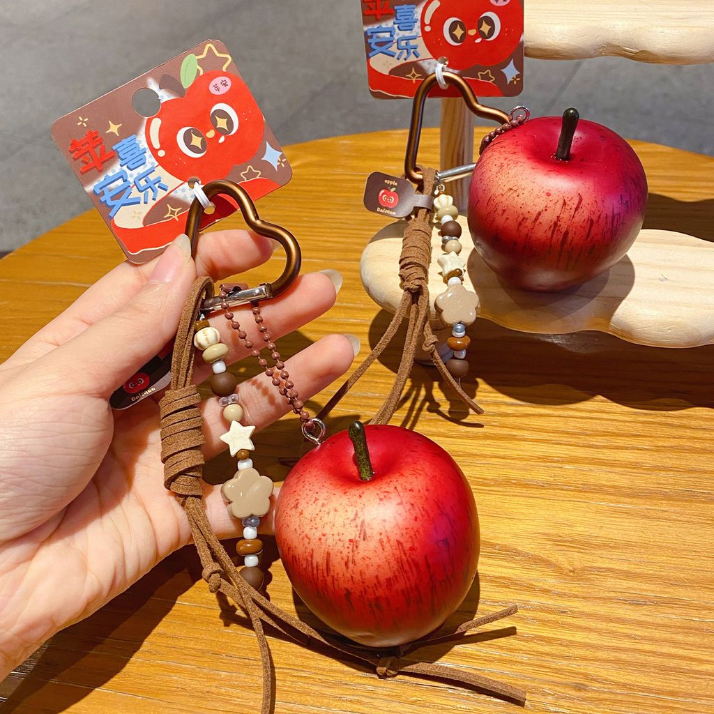 Two lucky apple keychain charms with red apple design displayed on a wooden table