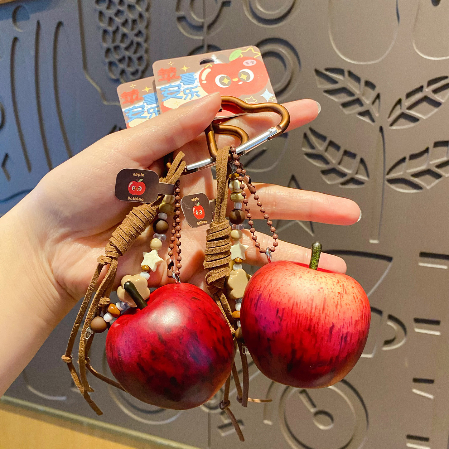 Two lucky apple keychain charms held in hand