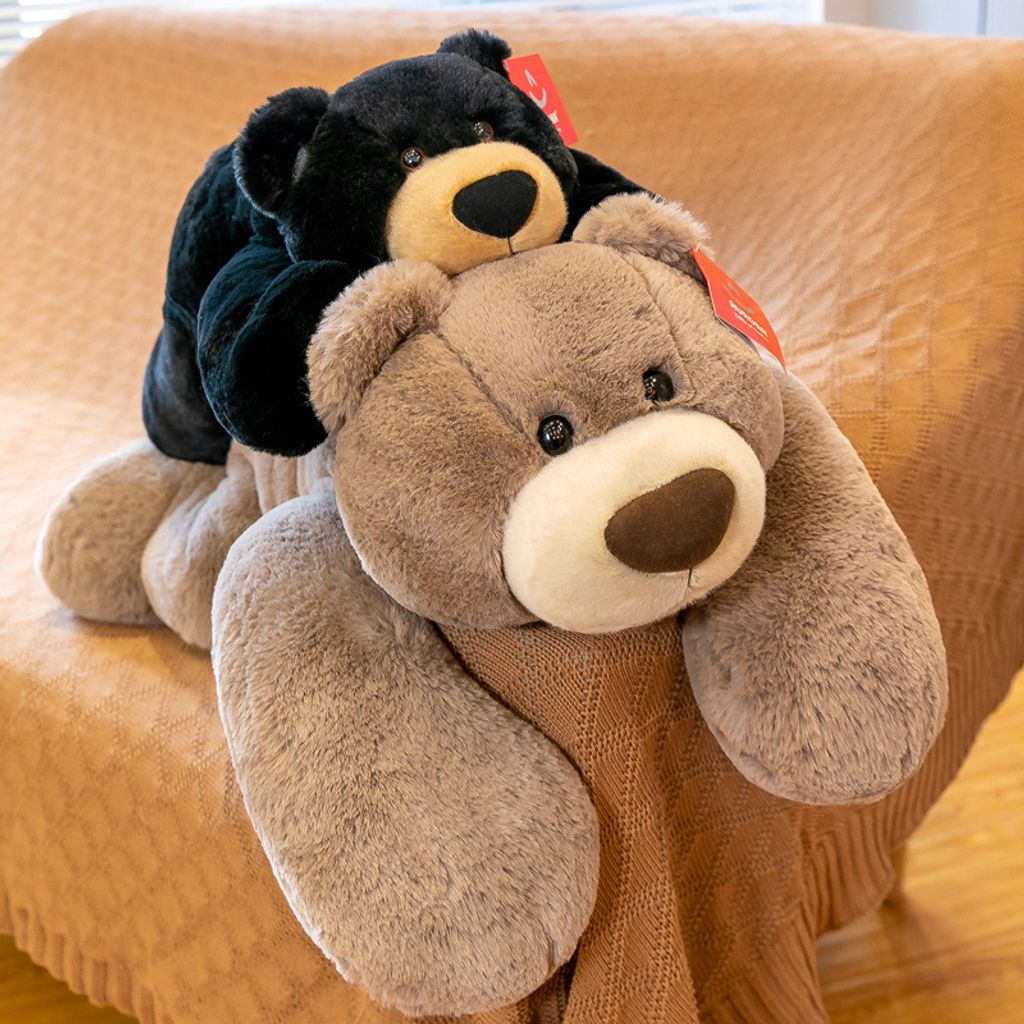 Bear lying plush toys stacked together on a sofa