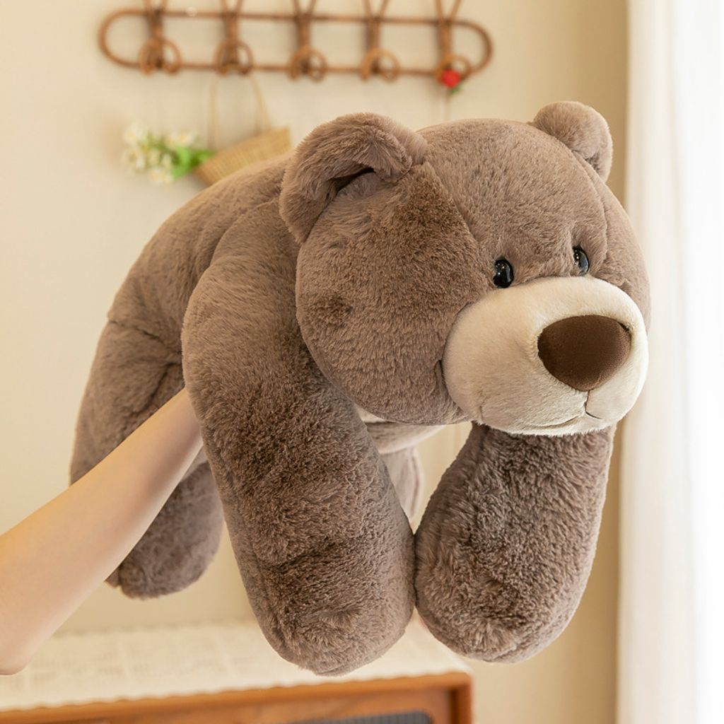 Brown bear lying plush toy held in hands