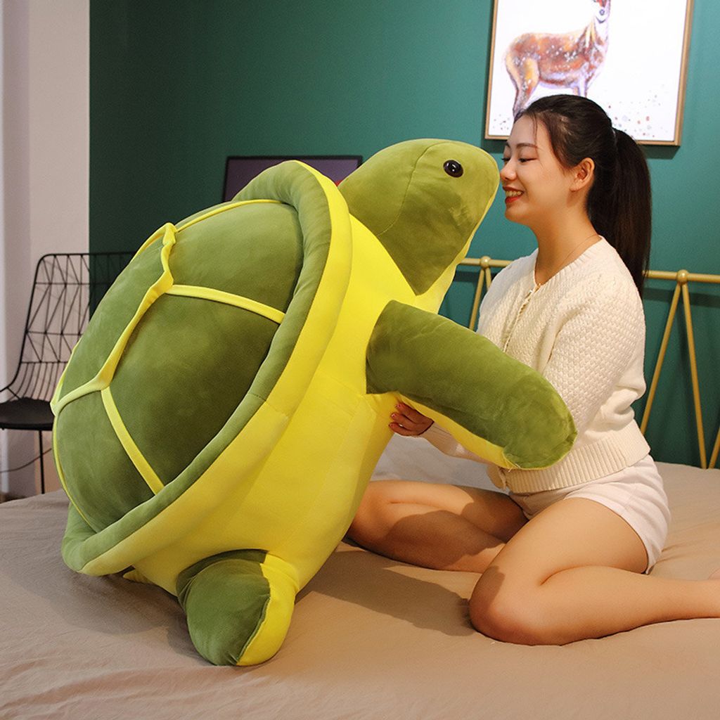 Giant turtle plush pillow held for hugging and size reference
