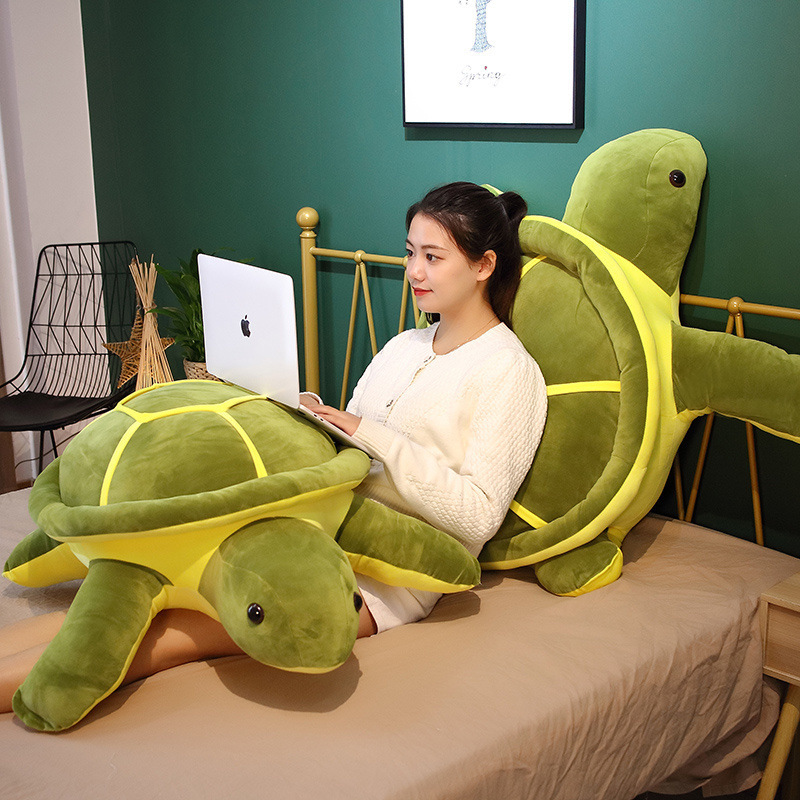 Giant turtle plush pillow used as a backrest on a bed