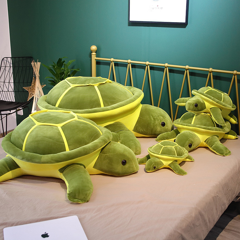 Giant turtle plush pillow shown in five sizes on a bed