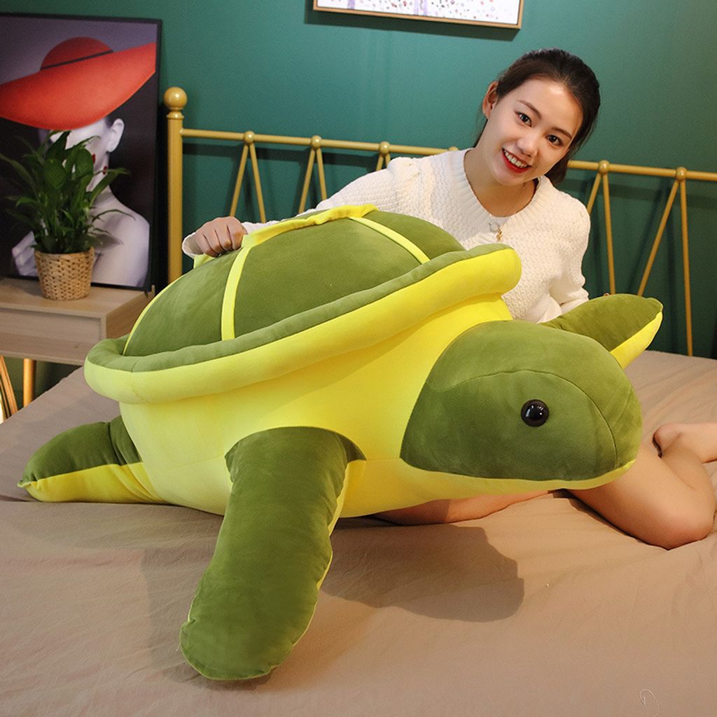 Oversized giant turtle plush pillow on a bed