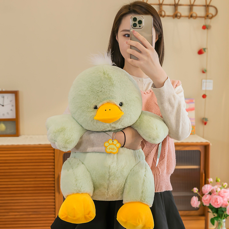 Green duck plush toy held in arms to show size and soft texture
