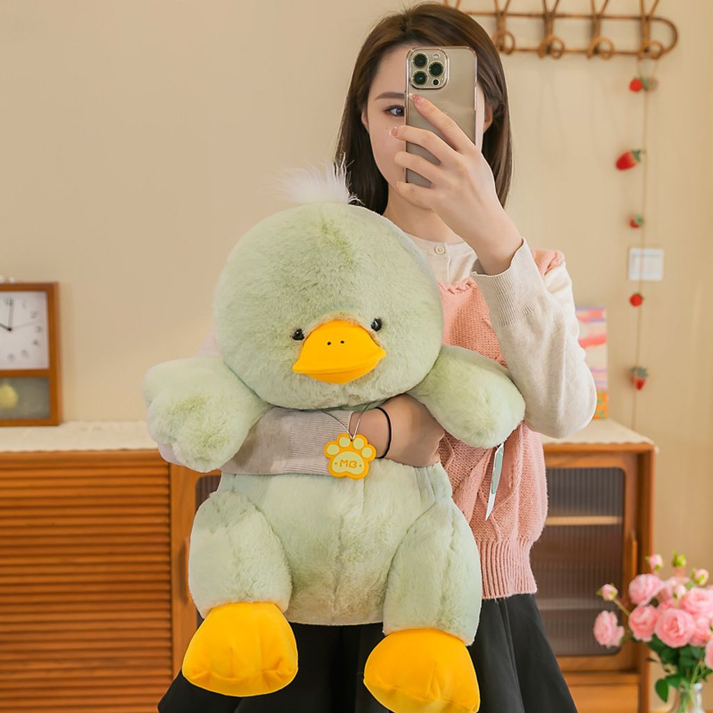 Green duck plush toy held in arms to show size and soft texture