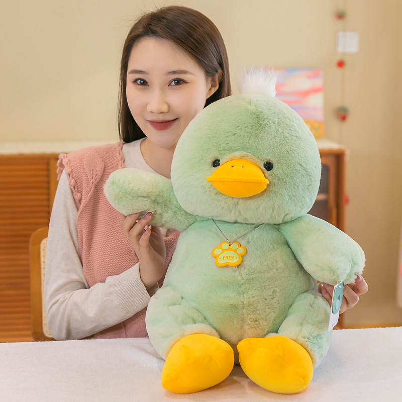 Green duck plush toy held in arms showing soft texture and size