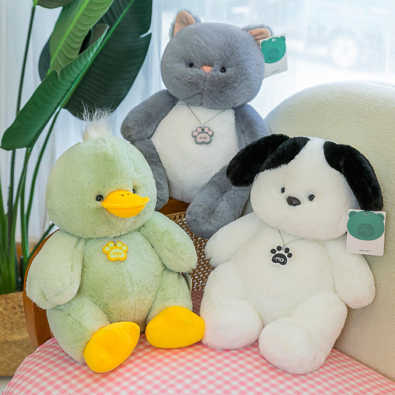 Gray cat green duck and white dog plush toys displayed together on a sofa