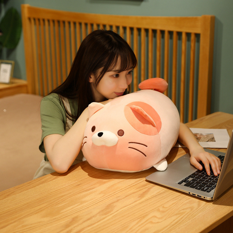 Cute round cat plush toy used as a soft pillow while resting at a desk