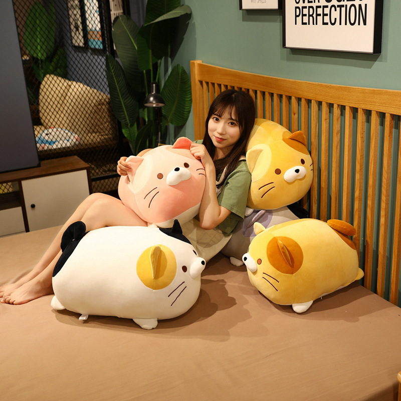 Cute round cat plush toys in multiple colors shown in a cozy bedroom setting