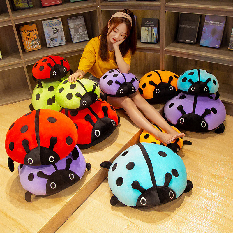 Cute ladybug plush pillow in multiple colors displayed on the floor