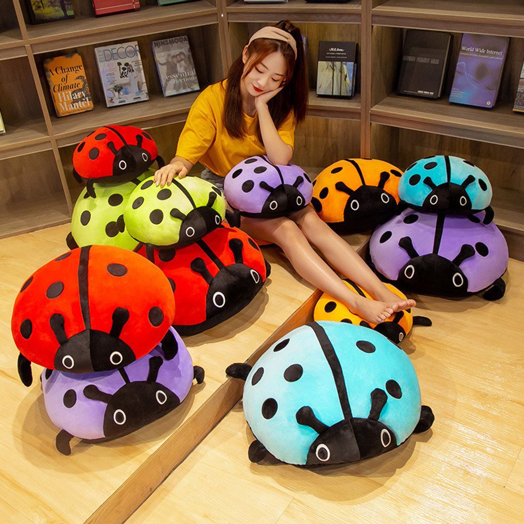 Cute ladybug plush pillow in multiple colors displayed on the floor
