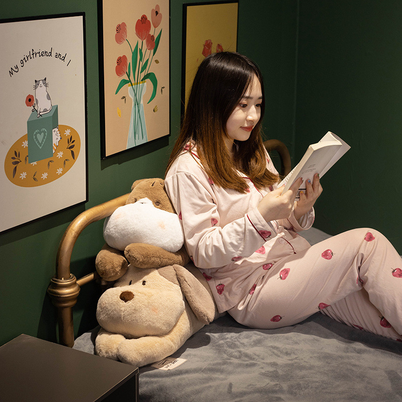 Cute lying animal plush pillow used for comfort while resting and reading, styled in a cozy bedroom environment
