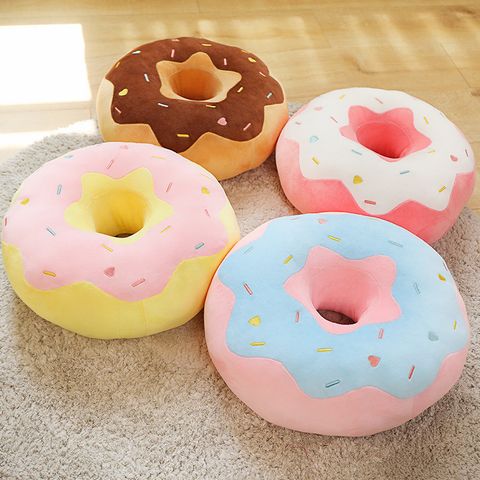 Donut plush pillow in pastel colors placed on a carpet