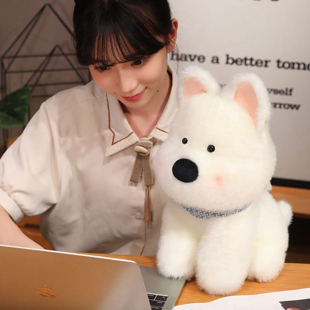 White Westie dog plush toy displayed beside a laptop