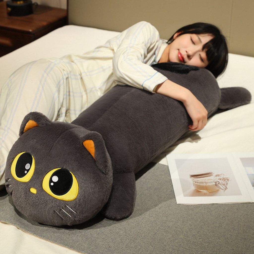 Black cute lying cat long plush pillow used as a hugging body pillow on bed