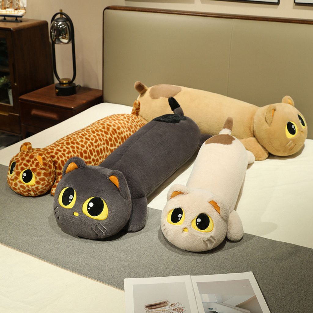 Various cute lying cat long plush pillows in different colors on bed
