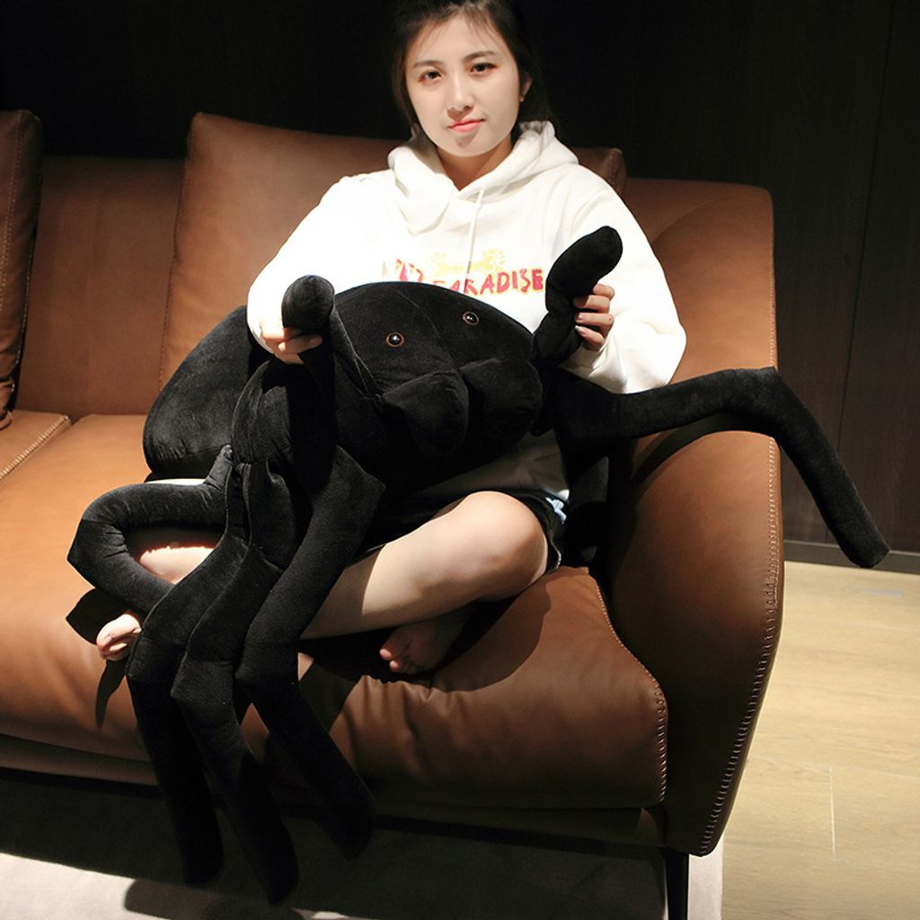Large spider plush pillow used as a hugging cushion on armchair