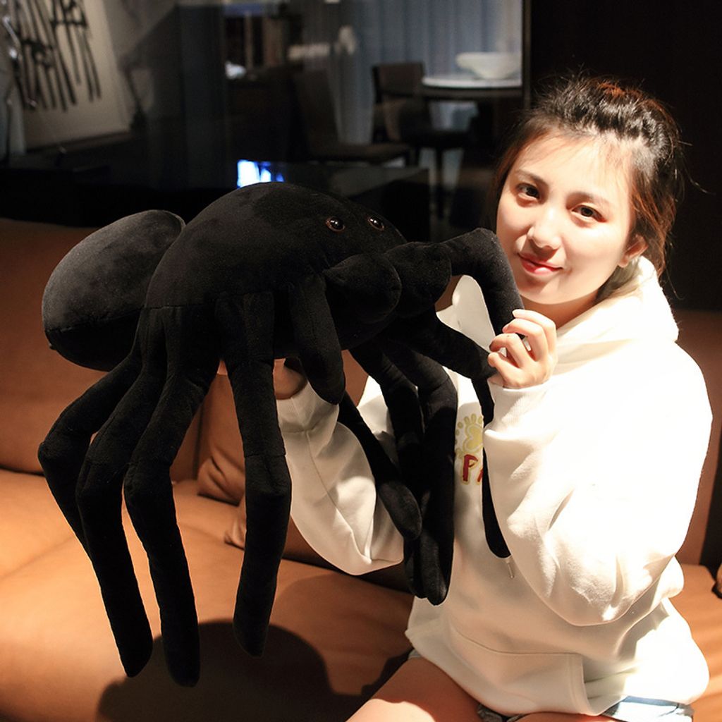 Giant spider plush pillow held up to show long legs and soft plush texture