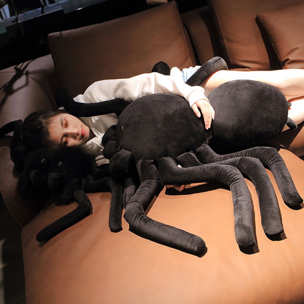 Giant spider plush pillow used as a body pillow on sofa