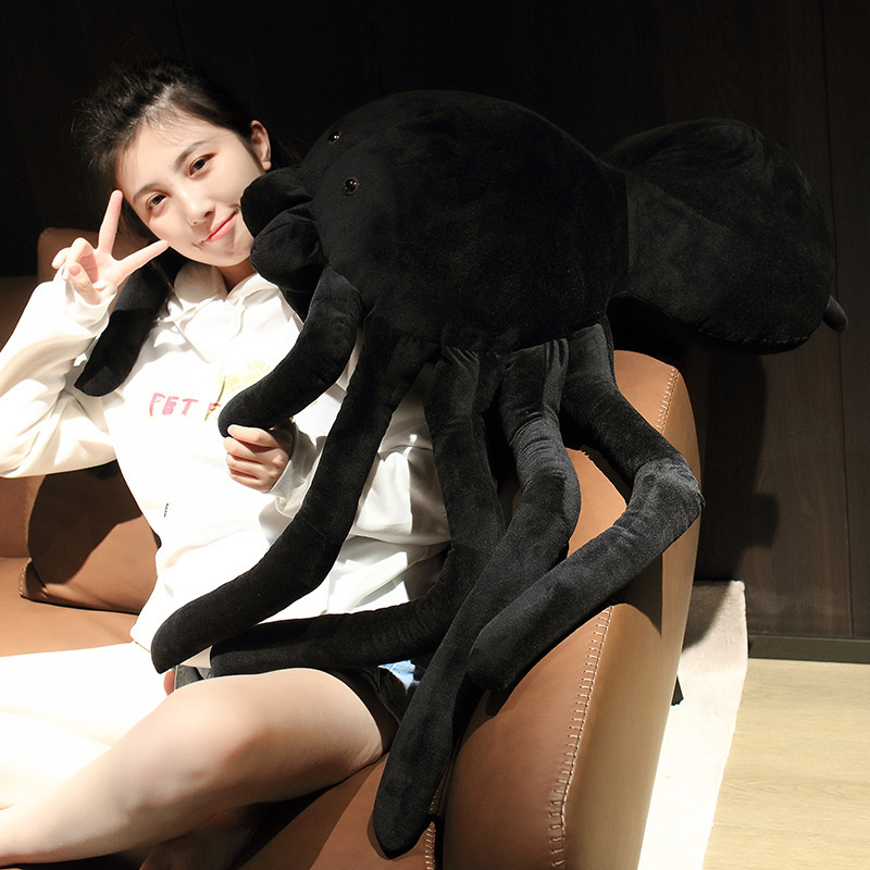 Giant spider plush pillow resting on sofa with long legs