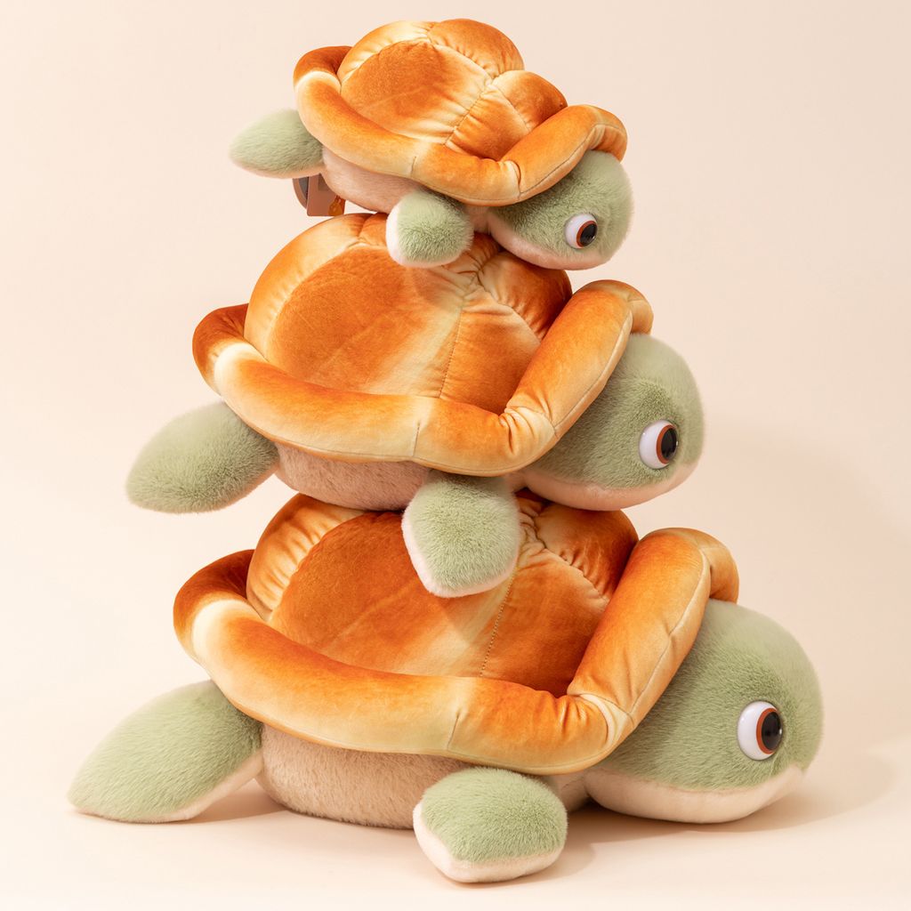 Three sizes of bread turtle plush toys stacked together showing soft bread shells and green flippers