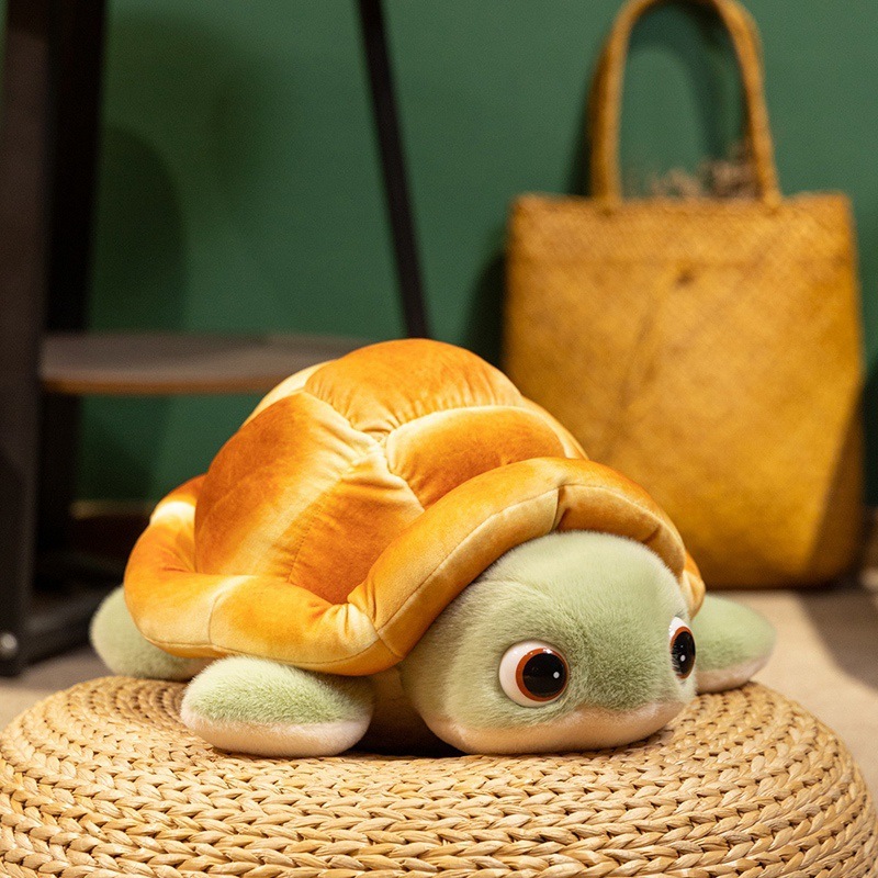 Bread turtle plush toy resting on a woven cushion, showing its round bread shell and cute green flippers