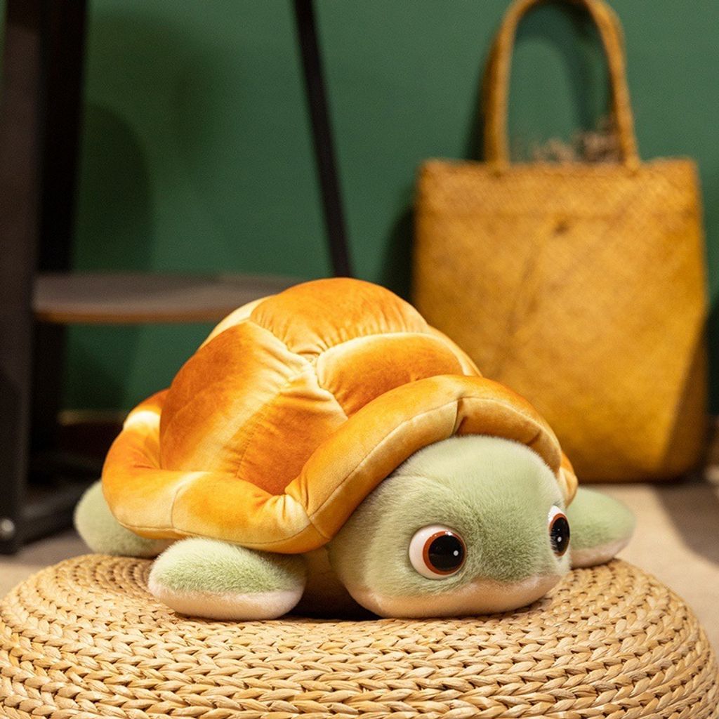 Bread turtle plush toy resting on a woven cushion, showing its round bread shell and cute green flippers