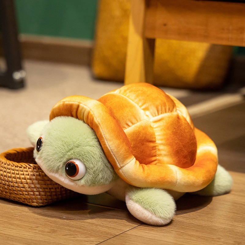 Bread turtle plush toy resting beside a woven basket, showing soft bread shell and green flippers