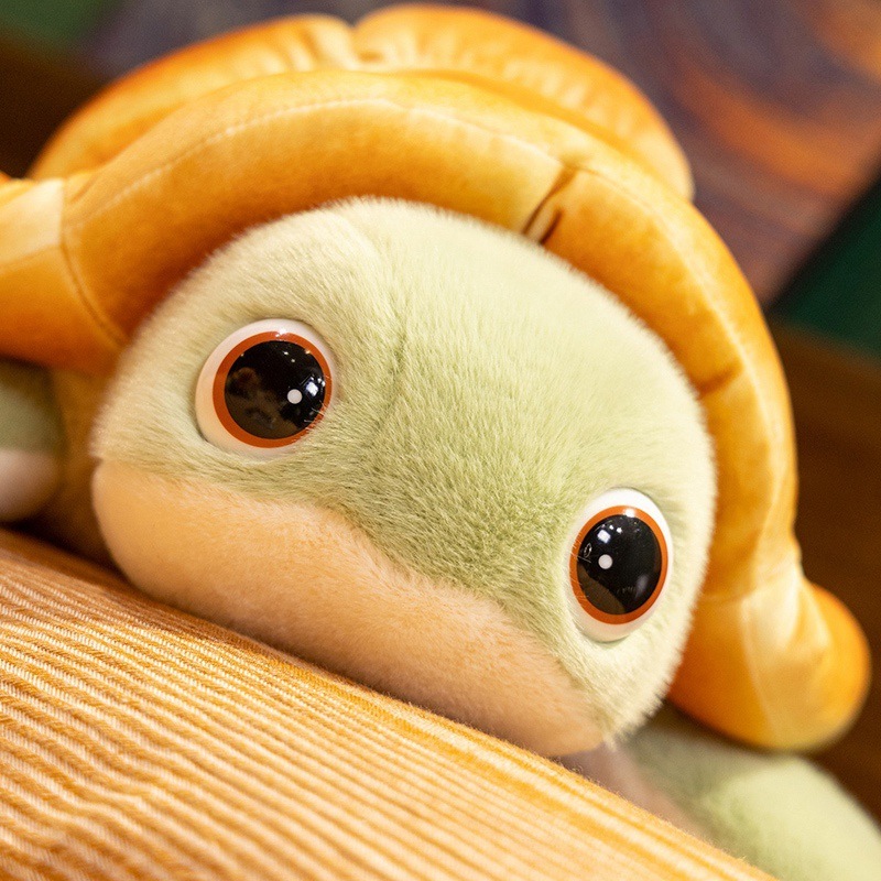 Close up of bread turtle plush toy face with big round eyes and soft green plush