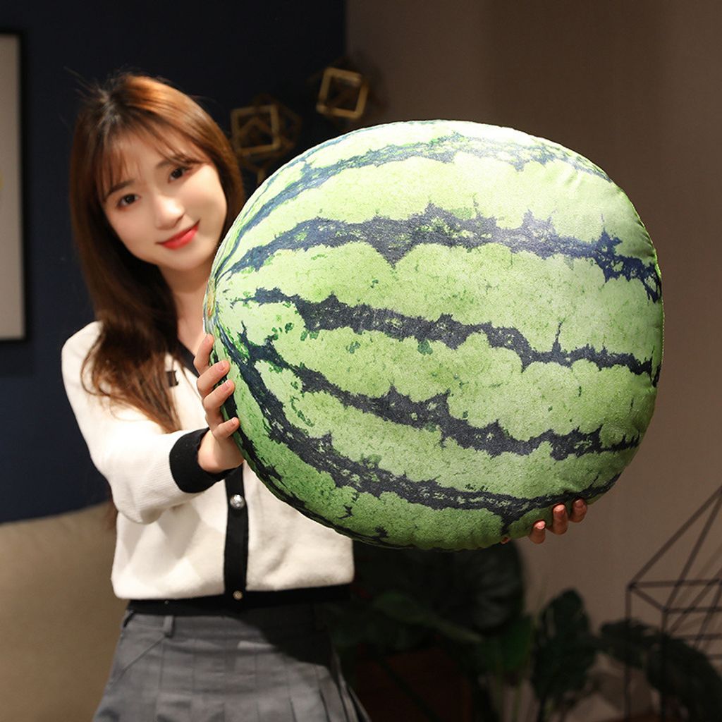 Realistic watermelon plush pillow with green striped design displayed in a cozy living room