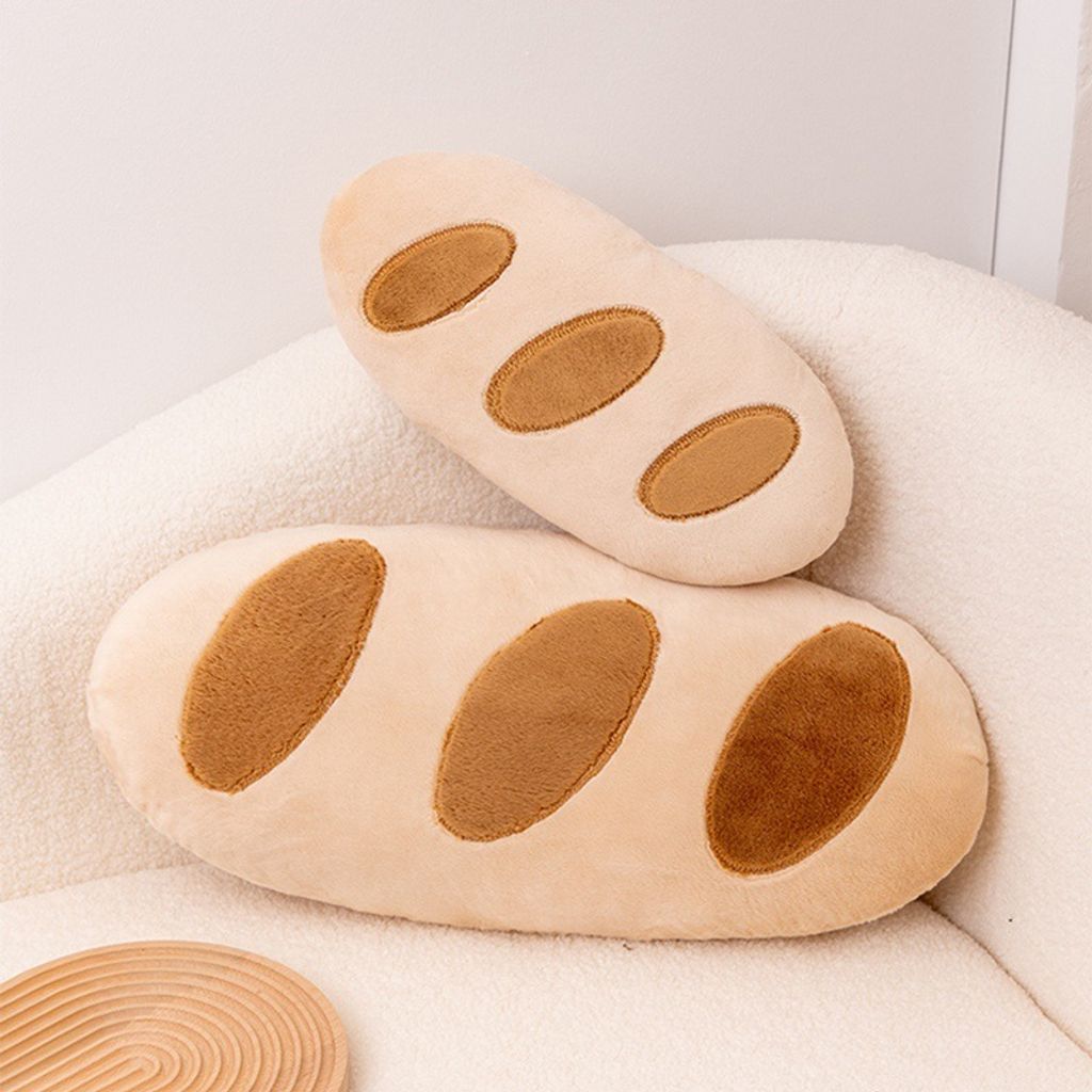 Baguette bread plush pillows in two sizes displayed on a cozy sofa