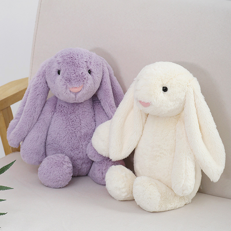 Purple and white lop ear bunny plush toys on a sofa