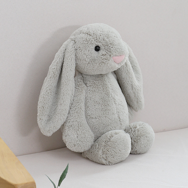 Gray lop ear bunny plush toy sitting on a sofa