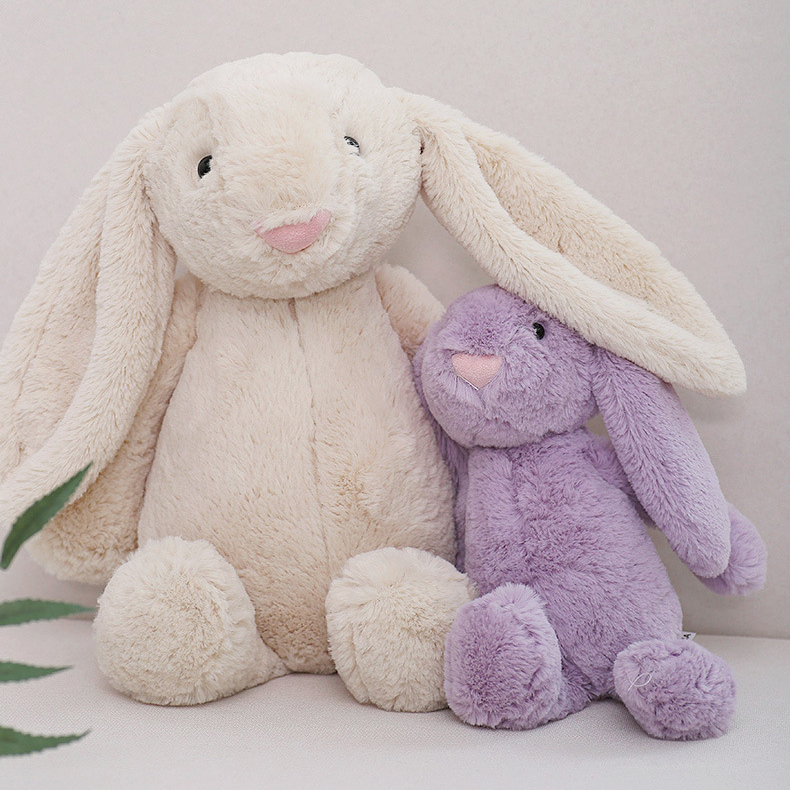Beige and purple lop ear bunny plush toys in two sizes on a sofa