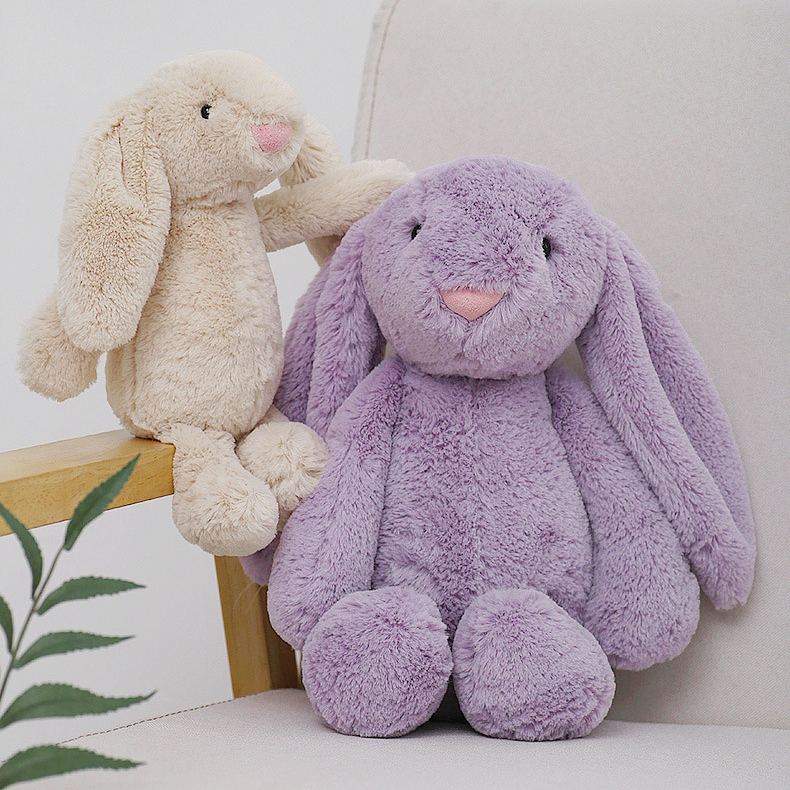 Beige and purple lop ear bunny plush toys sitting on a sofa