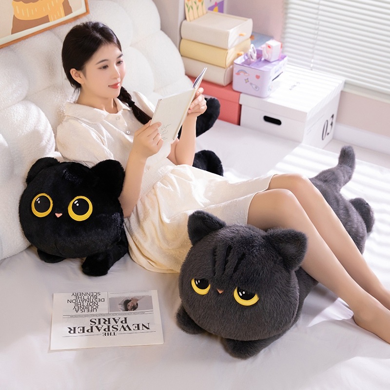 Gray and black lying cat plush pillows used as cozy cushions on a sofa